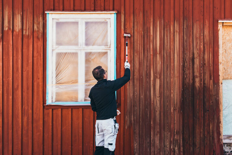 Måla rödfärg med pensel på förlängningsskaft