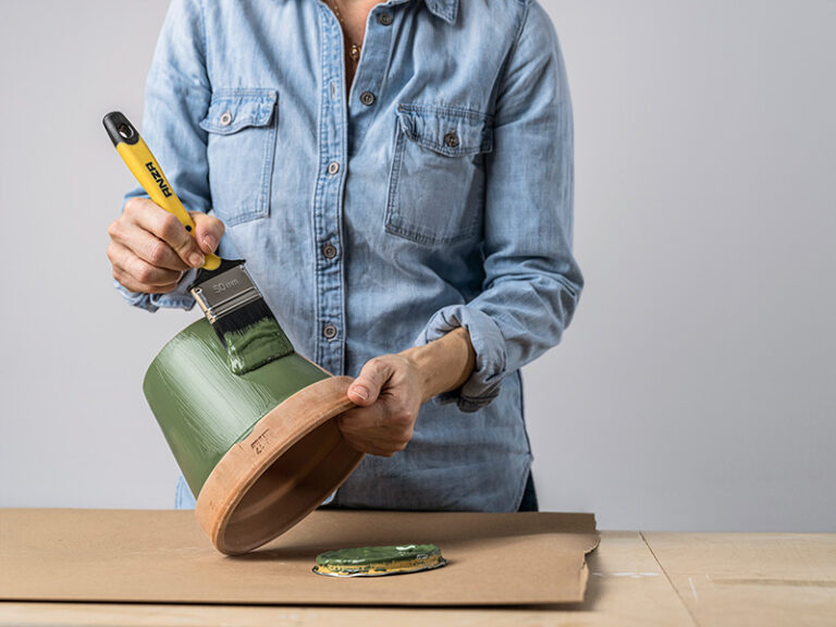 Kvinna som målar en kruka med en Basic-målarpensel